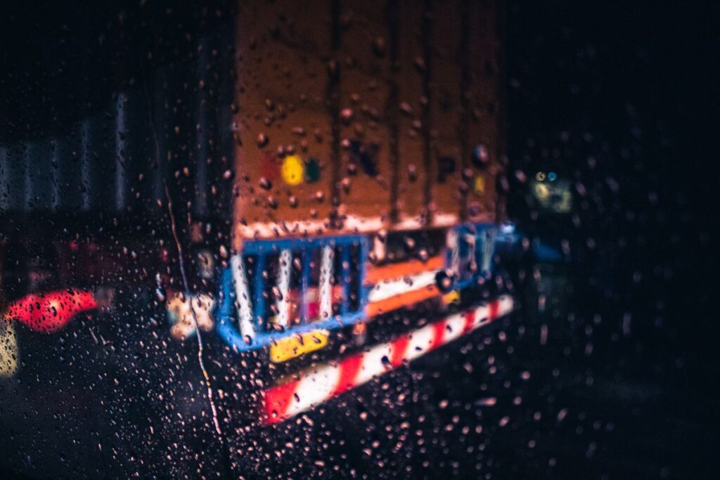 Blurry rain-covered windshield view of a truck driving in bad weather while towing